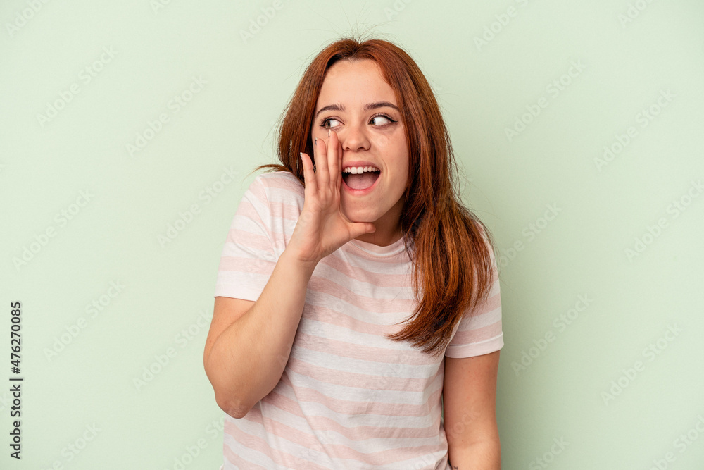 Fototapeta premium Young caucasian woman isolated on green background shouting excited to front.