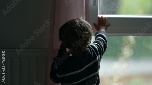 Little boy shutting window home. Child closes window