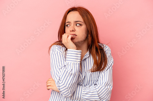 Young caucasian woman isolated on pink background biting fingernails, nervous and very anxious.