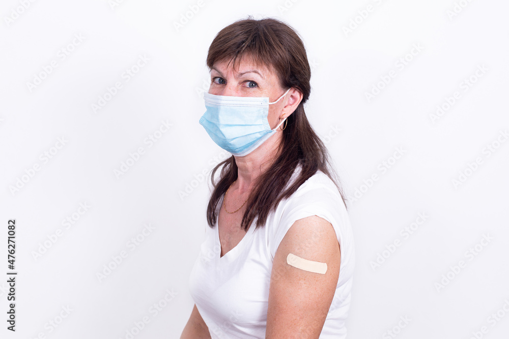 Adult woman in mask with bandage on shoulder after vaccination against coronavirus or flu. Mandatory prevention of elderly people for immunity from virus. person isolated on white background. Adult woman in mask with bandage on shoulder after vaccination against coronavirus or flu. Mandatory prevention of elderly people for immunity from virus. person isolated on white background.