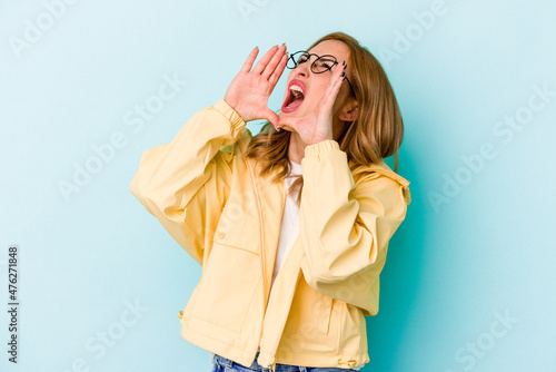 Young caucasian woman isolated on blue background shouting excited to front.