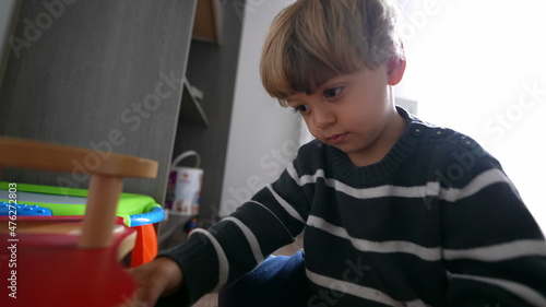 Child plays with toy car in room