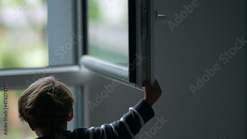 Child closing window. Toddler closes window