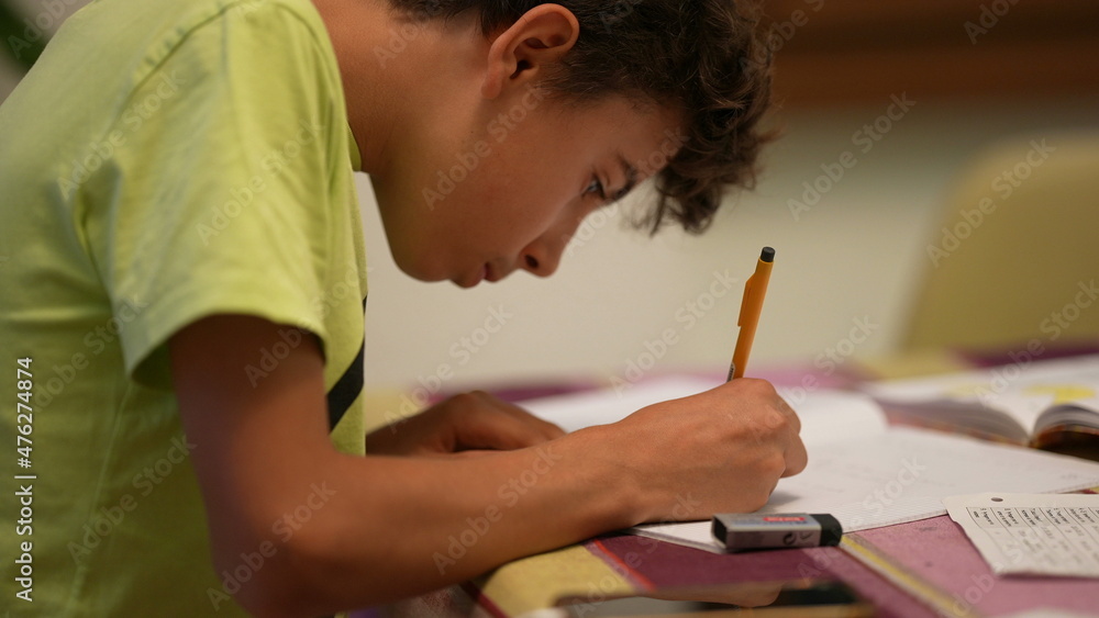 Adolescent kid doing homework studying at home, young boy studies Adolescent kid doing homework studying at home, young boy studies