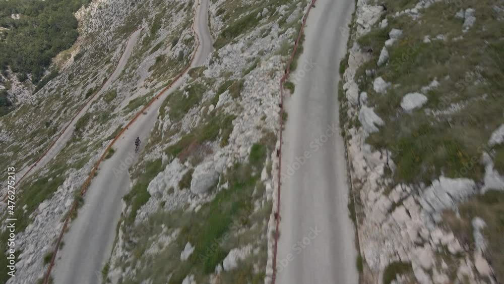 The cyclist descends on a narrow highway winding along the slope of the highest mountain in the natural park Biokovo Croatia. The cyclist descends on a narrow highway winding along the slope of the highest mountain in the natural park Biokovo Croatia.