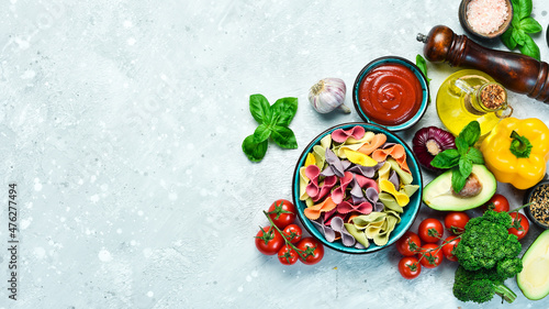 Colored dry pasta in a bowl on a gray stone background. Food. Top view. Free space for text.