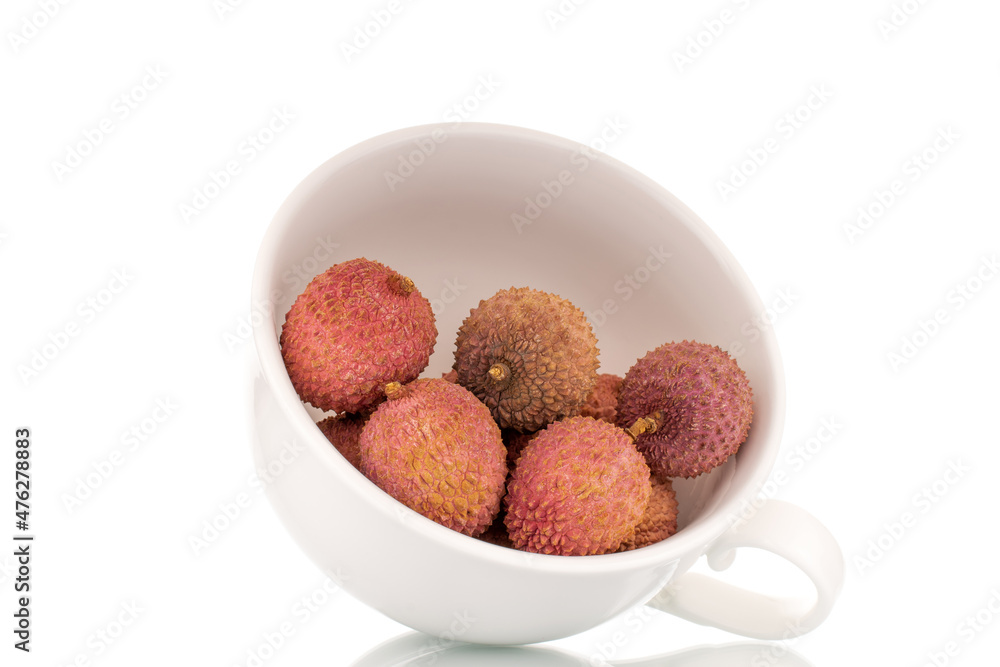 Several ripe sweet Litchi fruits with a white ceramic cup, close-up, isolated on white.