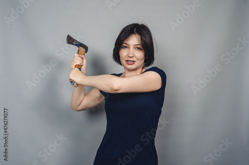 Woman with ax in hands. Threatening facial expression.