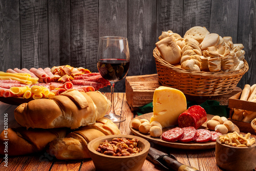 minced table with assorted cold cuts, salami, cheeses, homemade fat bread, peanuts and French fries with wooden plates and wicker basket