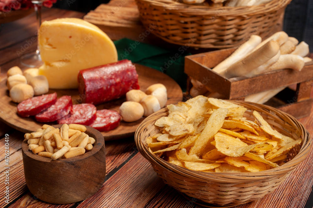 minced table with assorted cold cuts, salami, cheeses, homemade fat bread, peanuts and French fries with wooden plates and wicker basket