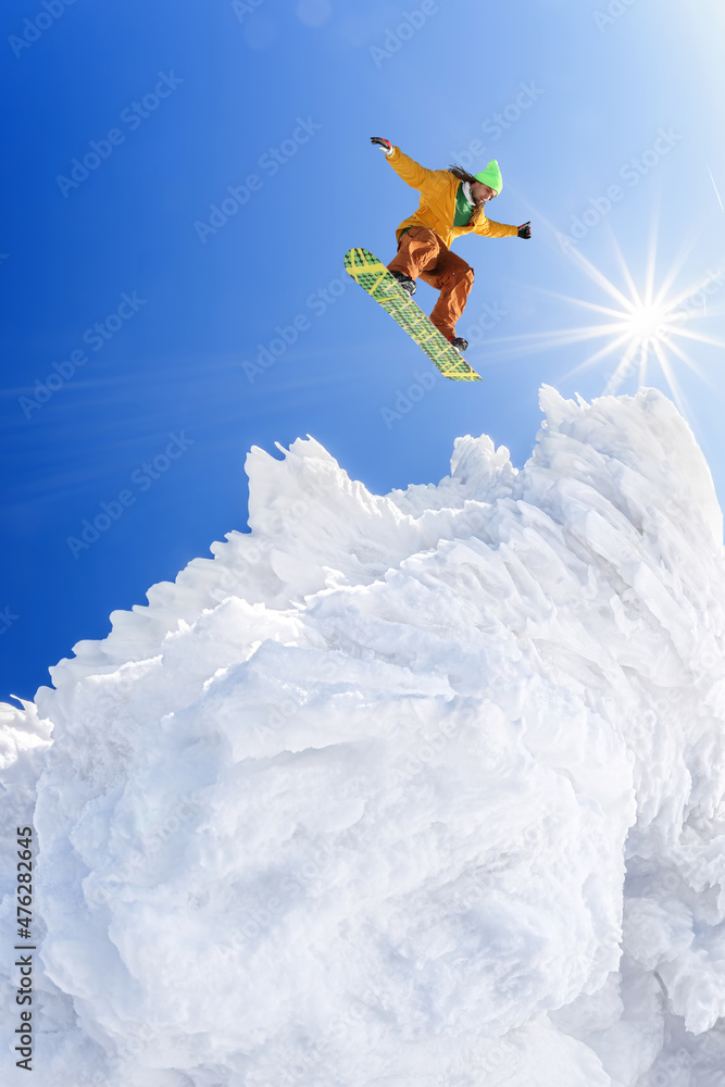 Snowboarder jumping against blue sky in high mountains