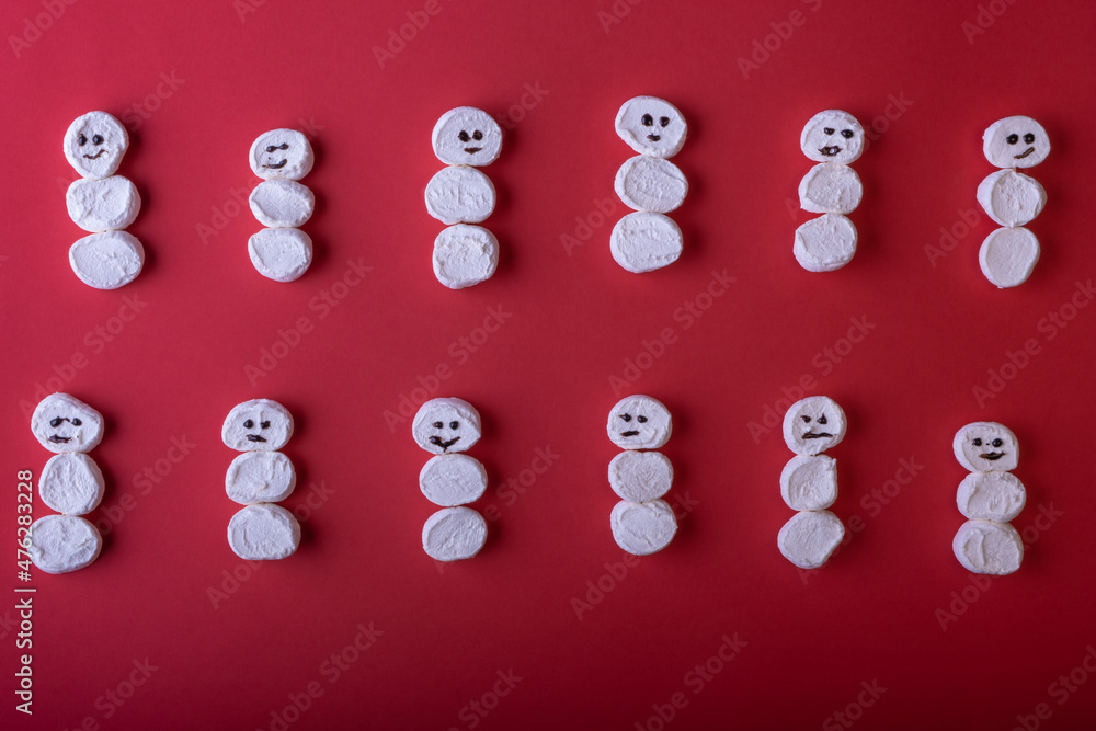 Lots of funny white marshmallow snowmen on a bright red Christmas background. Christmas and New Years concept. Winter greeting card Lots of funny white marshmallow snowmen on a bright red Christmas background. Christmas and New Years concept. Winter greeting card