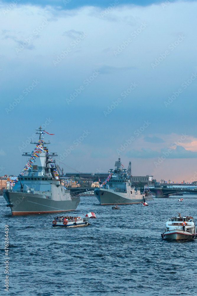Modern warships. Tourists from pleasure ships and the embankment look at the warships on the Neva. Before the naval parade in St. Petersburg, Russia