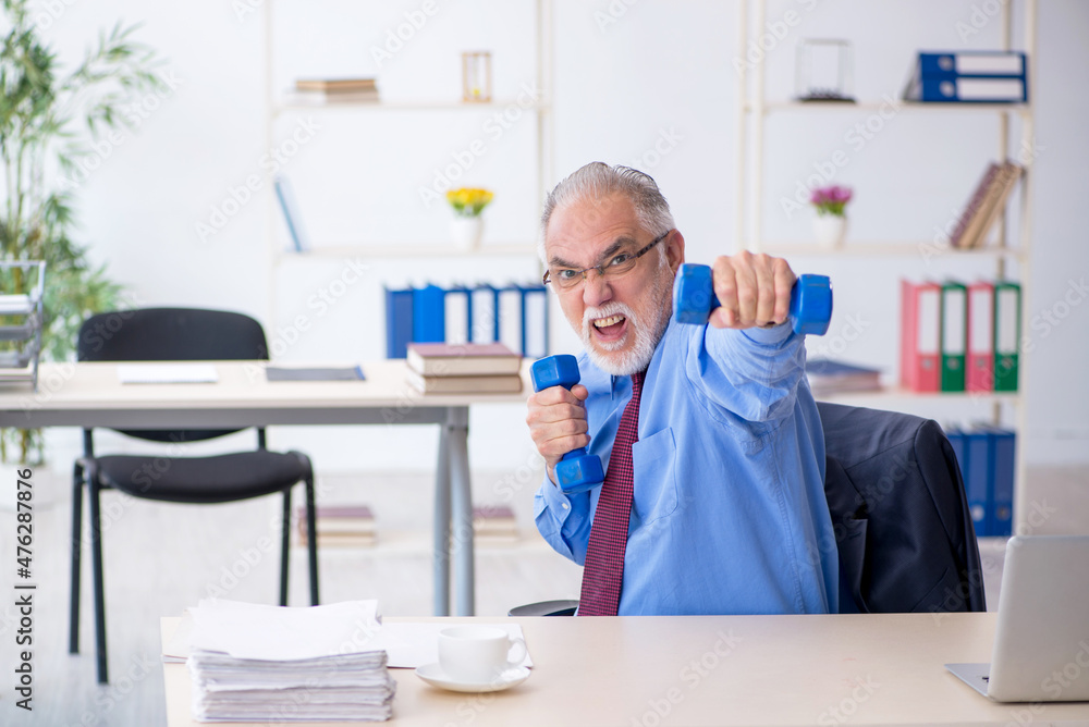 Old male employee doing sport exercises during break Old male employee doing sport exercises during break