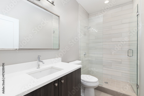 A luxury bathroom with a wood vanity  marble countertop  and a tiled shower.