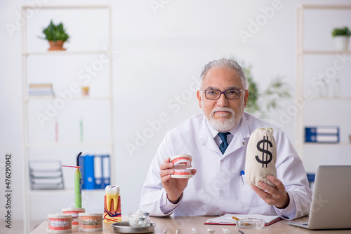 Old male doctor dentist in remuneration concept