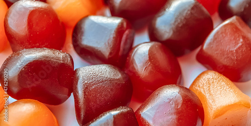 Selective focus.Close-up texture of red, orange and purple multivitamin gummies on white background photo