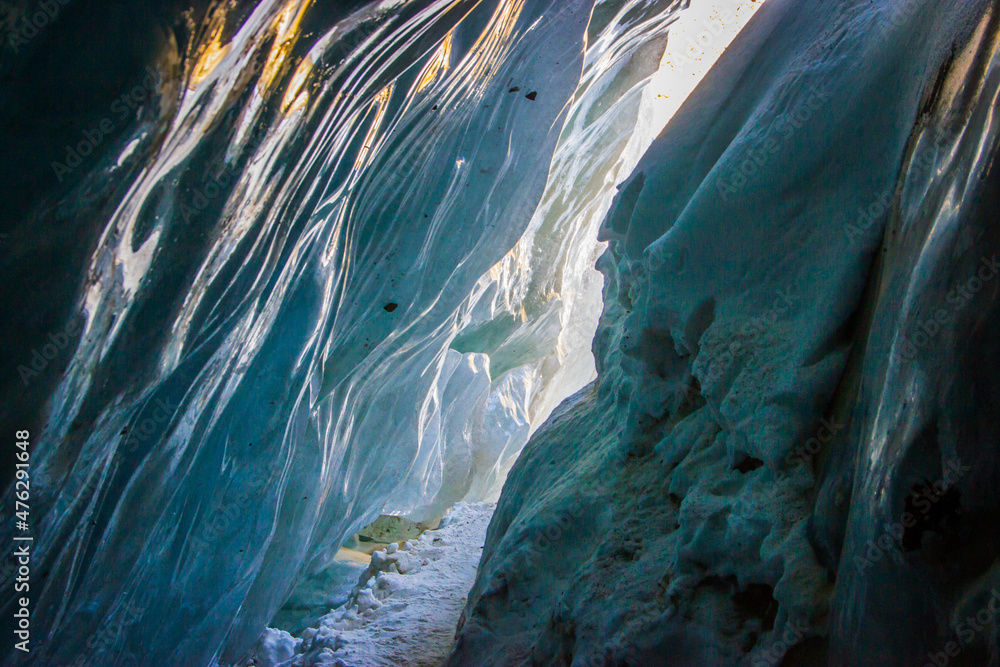 Ice cave of the Bogdanovich glacier - inside view. Blue ice, daylight. December, Kazakhstan.
