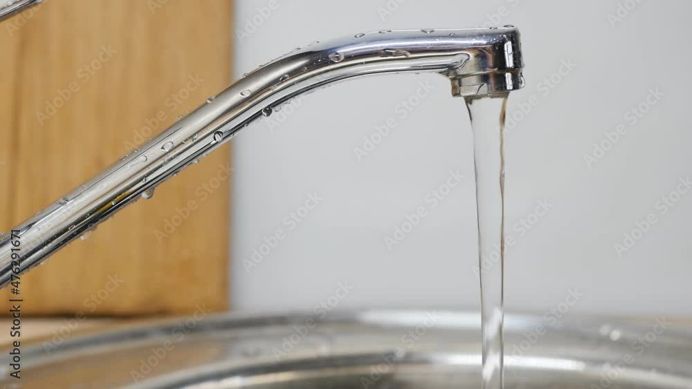 dolly shot, close-up, DOF: water is flowing from the faucet in the kitchen. dolly shot, close-up, DOF: water is flowing from the faucet in the kitchen.