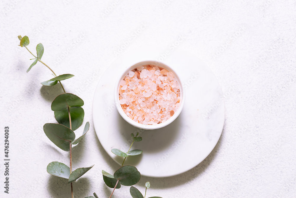 Pink Himalaya salt and fresh aromatic eucalyptus branches on white marble podium top view. Spa and wellness composition. Pink Himalaya salt and fresh aromatic eucalyptus branches on white marble podium top view. Spa and wellness composition.