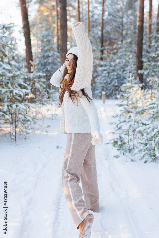 Beautiful woman standing among snowy trees in winter forest and enjoying first snow. Wearing hat, knitted scarf and warm coat. Wanderlust and casual winter style Beautiful woman standing among snowy trees in winter forest and enjoying first snow. Wearing hat, knitted scarf and warm coat. Wanderlust and casual winter style