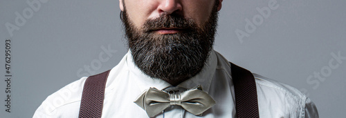 Photo Portrait of handsome bearded man in white shirt and bow tie, suspenders