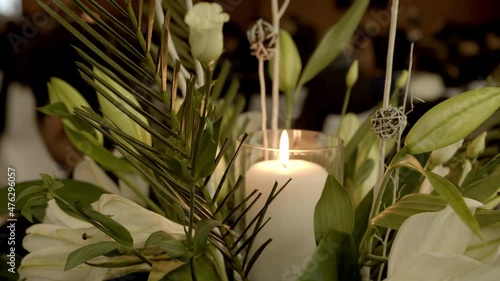 The burning candle surrounded by blooming flowers during the Vietnamese funeral service in 4K