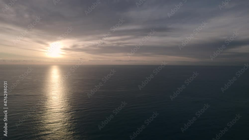 Horizon over calm Mediterranean Sea during bright idyllic beautiful sunrise. Glowing sun, smooth seascape, gray color cloudy sky background. No people, morning scenery. Spain, Calpe Horizon over calm Mediterranean Sea during bright idyllic beautiful sunrise. Glowing sun, smooth seascape, gray color cloudy sky background. No people, morning scenery. Spain, Calpe