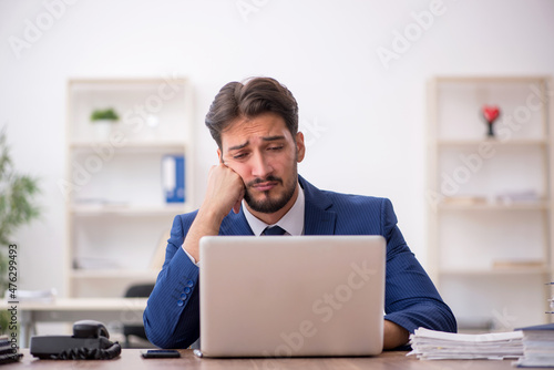 Young male employee unhappy with excessive work in the office