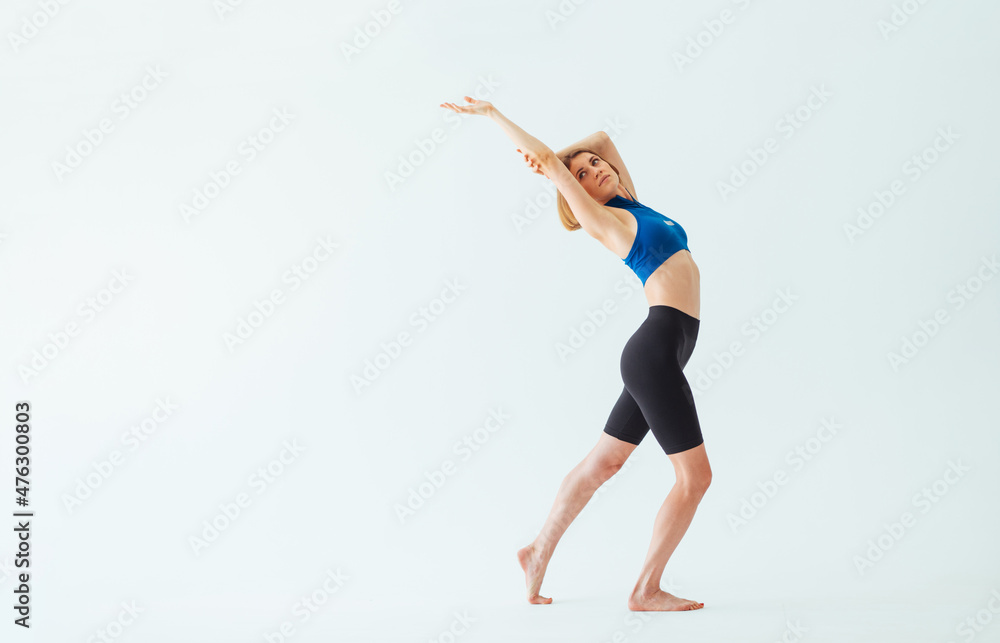 Beautiful athletic woman is engaged in stretching on a white background, bends her body back