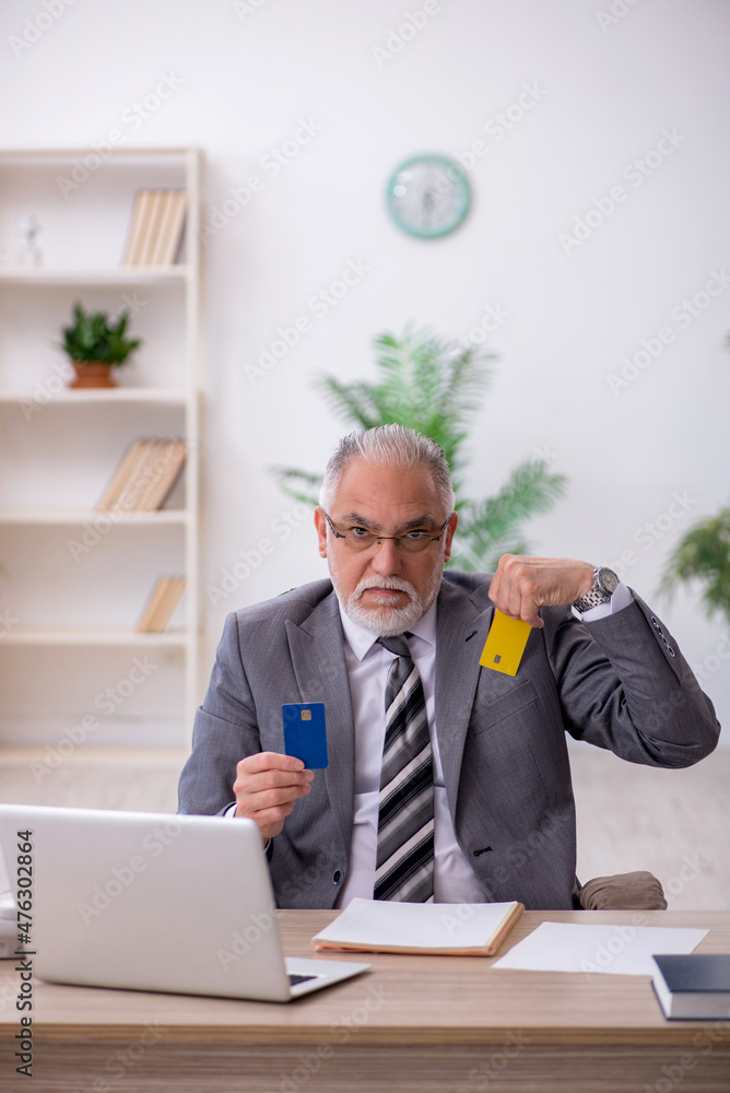 Old male employee holding credit card in the office Old male employee holding credit card in the office