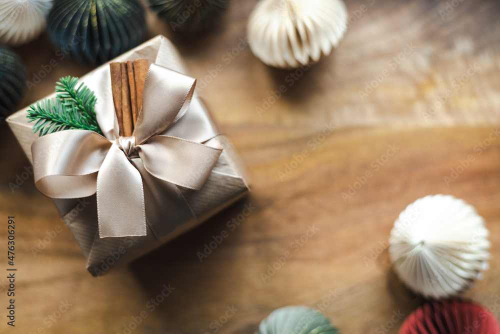 A beautifully wrapped Christmas present with natural decor on a wooden background. A beautifully wrapped Christmas present with natural decor on a wooden background.