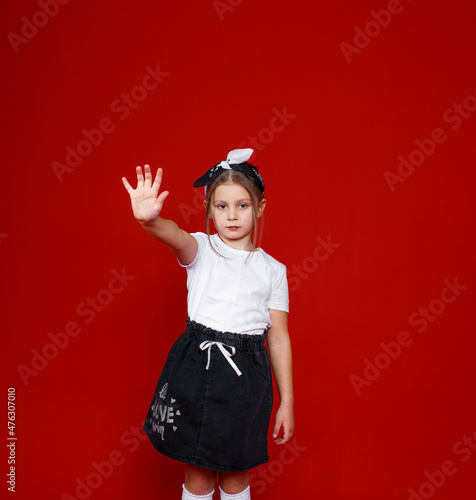 Portrait of a beautiful little girl posing on an isolated red background. extend your arm forward stop