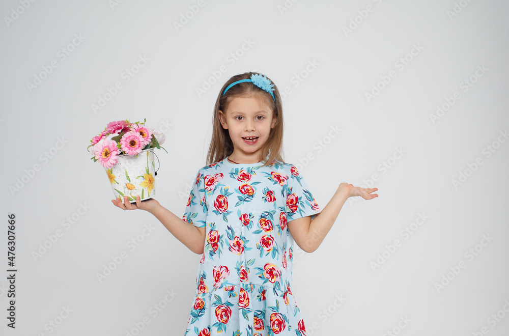 Portrait of a beautiful little girl in a bright dress holding a pot of flowers in her hand on an isolated white background.