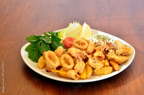 fried calamare with greens on wood table photo