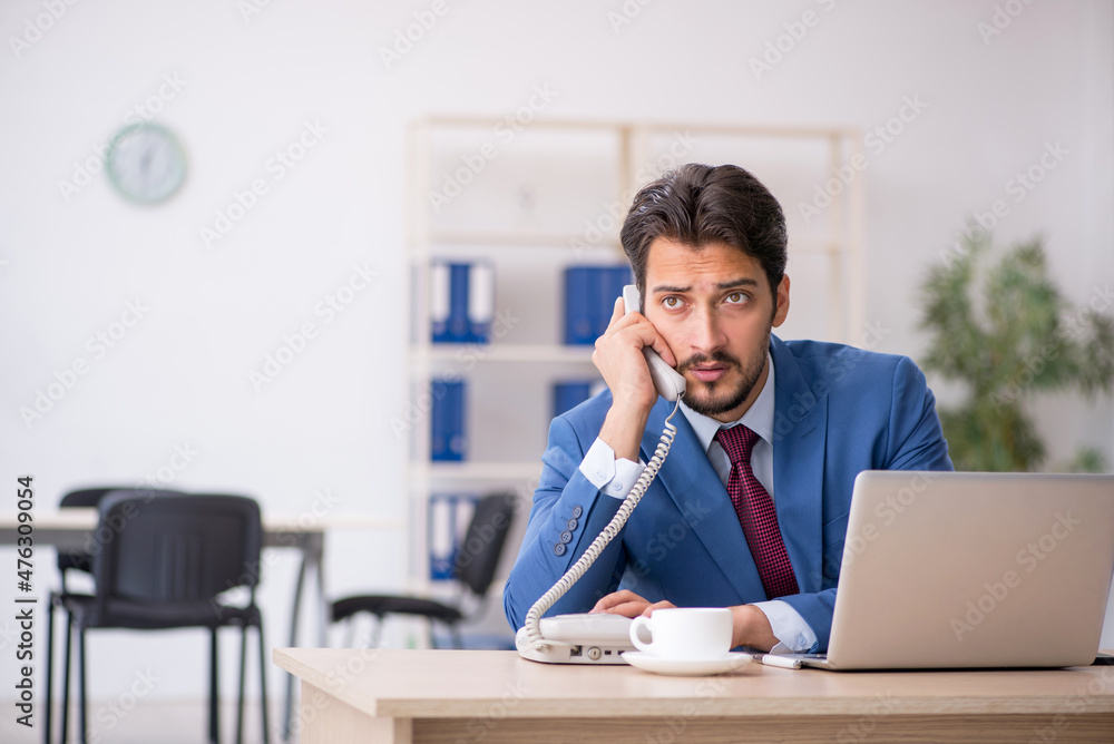 Naklejka premium Young male employee sitting at workplace