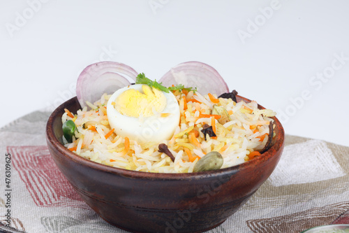 Fresh Egg biryani with a half-cut boiled egg served in a wooden bowl  isolated on white background