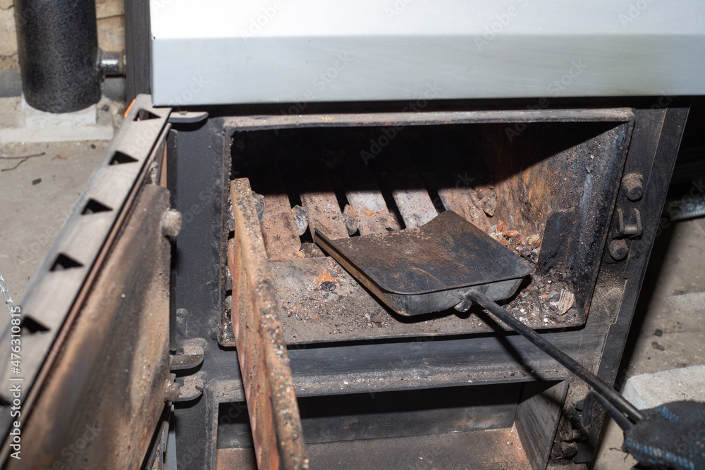 Cleaning the solid fuel boiler from the remains of firewood and coal. Boiler with an open damper. Heating efficiency in the house Cleaning the solid fuel boiler from the remains of firewood and coal. Boiler with an open damper. Heating efficiency in the house