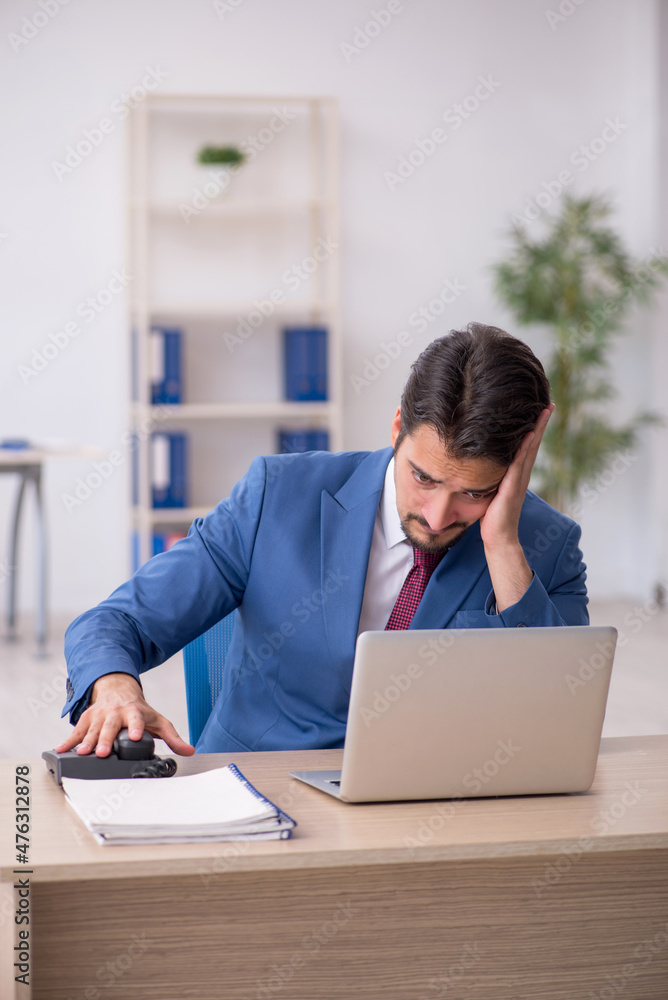 Young male employee unhappy with excessive work in the office Young male employee unhappy with excessive work in the office