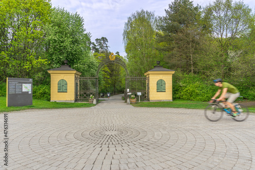 Blurred cyclist passing the entrance to big park in the middle of Stockholm photo