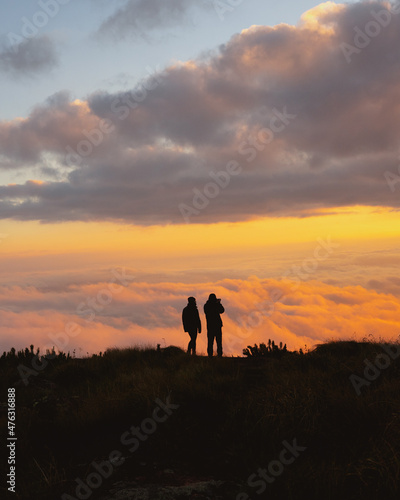 silhouette of people enjoying sunset in the mountains above the clouds, adventure
