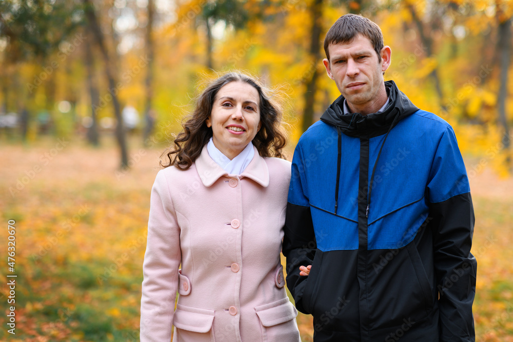 A couple walks in an autumn park along a path. Beautiful nature and trees with yellow leaves. A couple walks in an autumn park along a path. Beautiful nature and trees with yellow leaves.