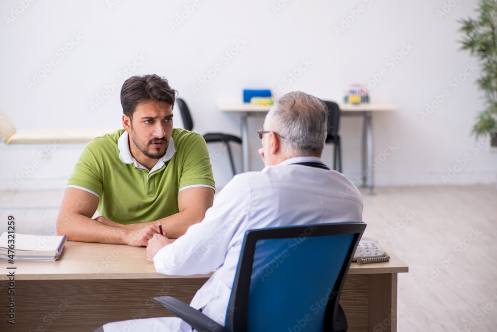 Fototapeta premium Young man visiting old male doctor