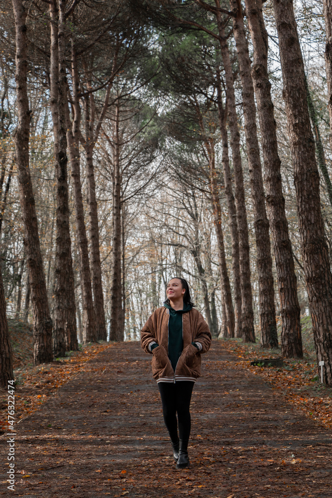 Beautiful girl walking in nature, looking up. Girl in autumn clothes. Outdoor portrait of alone, beautiful, young girl walking in autumn forest. Full length photo. Beautiful girl walking in nature, looking up. Girl in autumn clothes. Outdoor portrait of alone, beautiful, young girl walking in autumn forest. Full length photo.