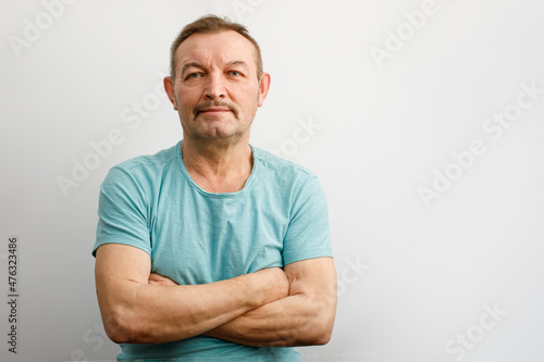 Portrait of a benevolent elderly man with a mustache. A man stands with his arms crossed and smiles