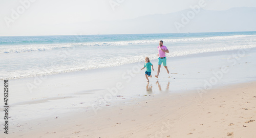 dad and kid boy family running on summer beach, copy space, family sport