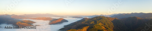 Autumn mountain landscape panorama. Peaks above the fog. Drone view.