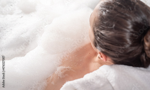 Woman relaxing in hot bath tub with soap foam