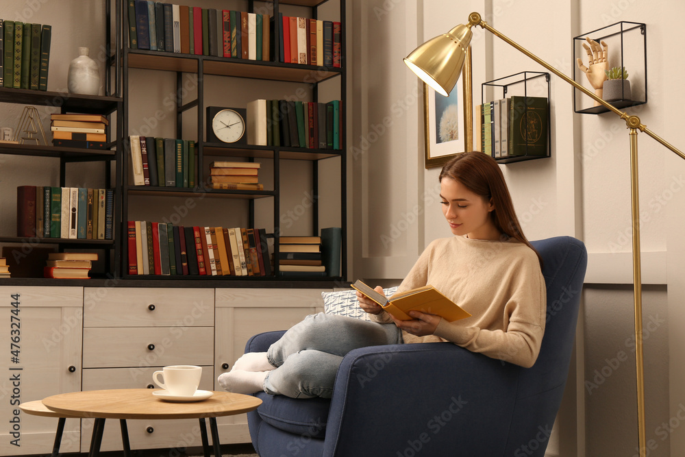Young woman reading book in armchair indoors. Home library Young woman reading book in armchair indoors. Home library