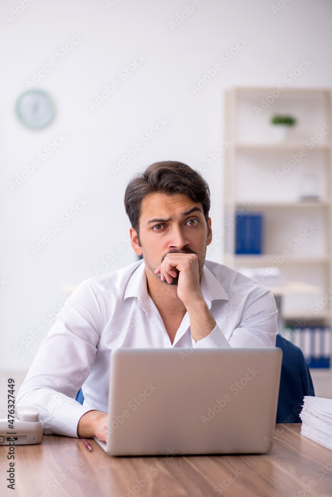 Young male employee and too much work in the office Young male employee and too much work in the office